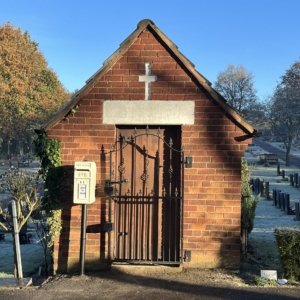 A photo of Cliptone Cemetery, a small building with a cross and a postbox.